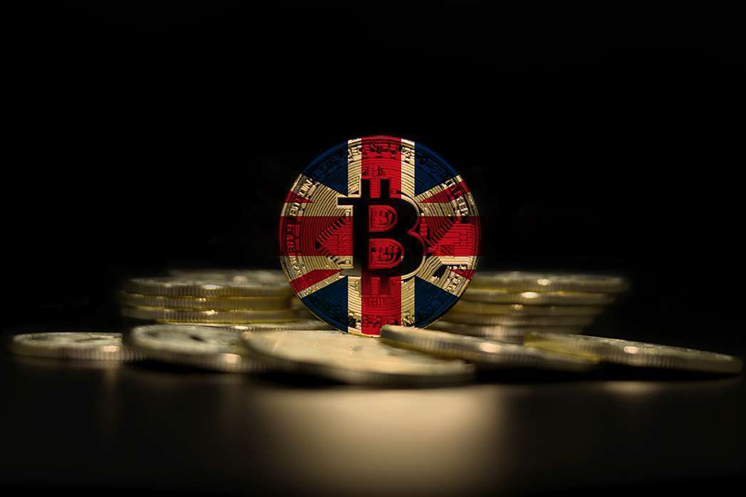 The British flag sits on top of a stack of coins, symbolizing the intersection of traditional finance and crypto currency.