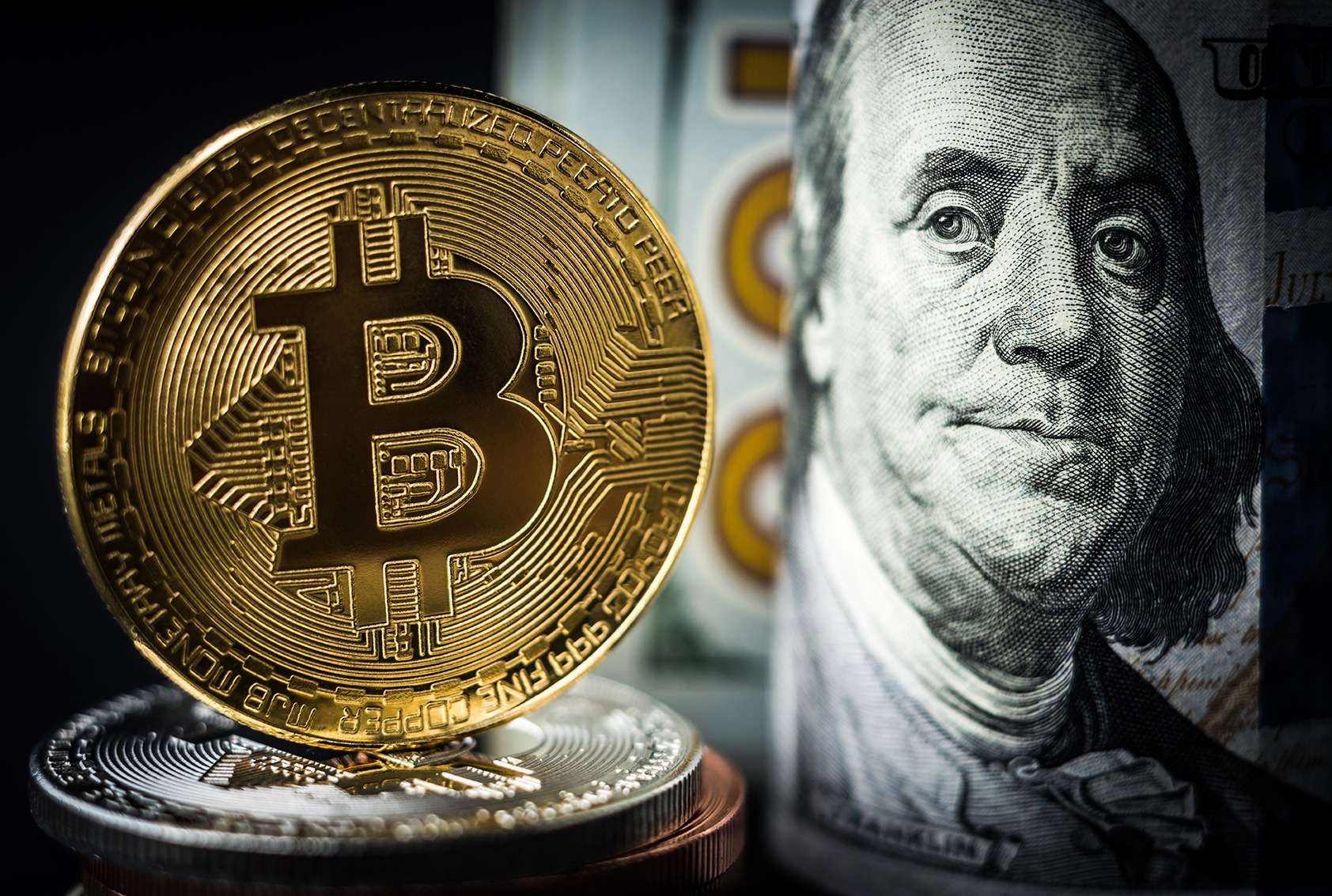 A crypto Bitcoin sits on top of a stack of dollars.