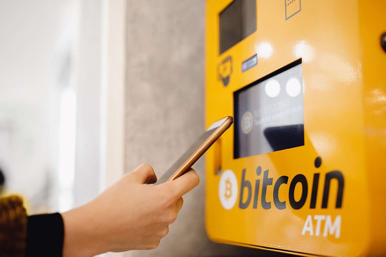 A person using a cell phone to use a bitcoin atm for ukcrypto.