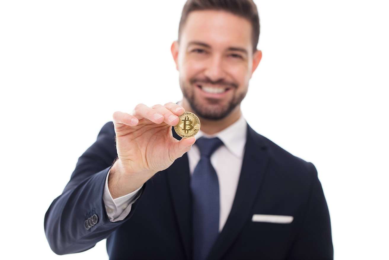 A businessman holding up a bitcoin, demonstrating the potential of UKCrypto on a white background.