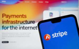 Stripe Payment provider logo seen on the smartphone and Stripe website on the blurred background.