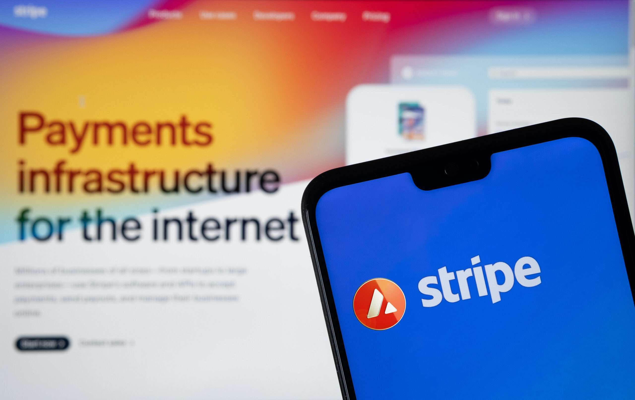 Stripe Payment provider logo seen on the smartphone and Stripe website on the blurred background.