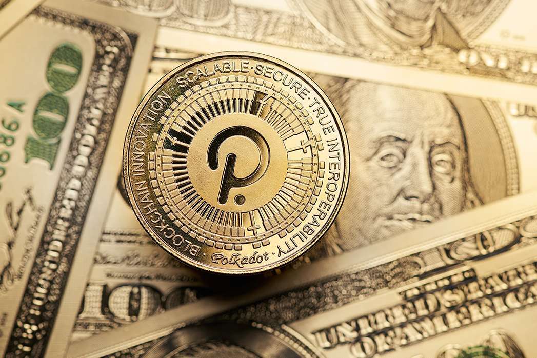 Close-up of golden Polkadot cryptocurrency on 100 dollar bills.