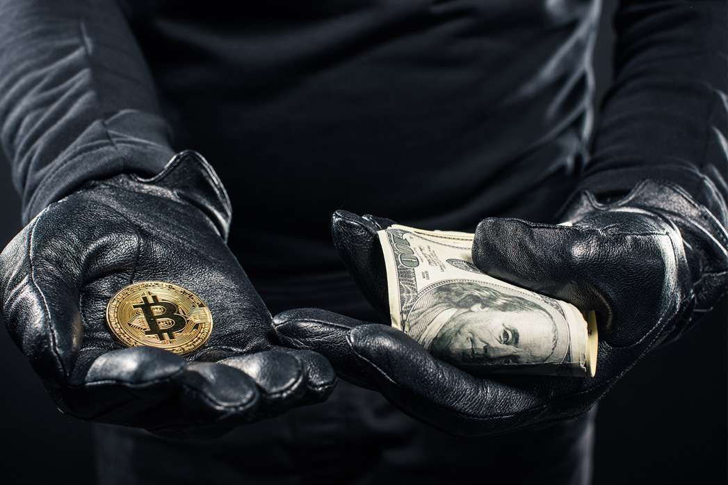 Close-up view of dollars and bitcoin in hands of thief