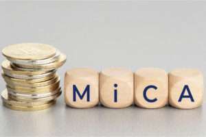 MiCA or Markets in Crypto Assets concept. Stacked cryptocurrency coins and wooden blocks with text.