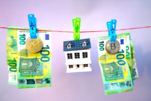 Money Laundering in cryptocurrency and Real Estate. Washed Euro note and bitcoin on drying. A house and one hundred 100 euros banknotes are drying on a clothesline. Money Laundering Risks in Real Estate.