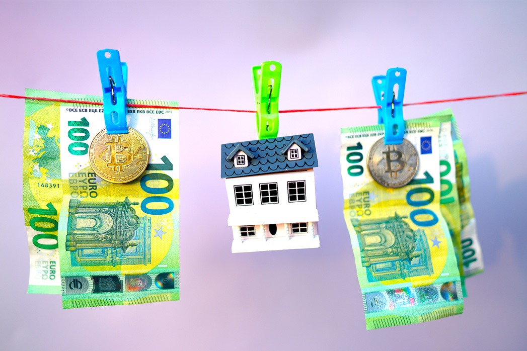 Money Laundering in cryptocurrency and Real Estate. Washed Euro note and bitcoin on drying. A house and one hundred 100 euros banknotes are drying on a clothesline. Money Laundering Risks in Real Estate.