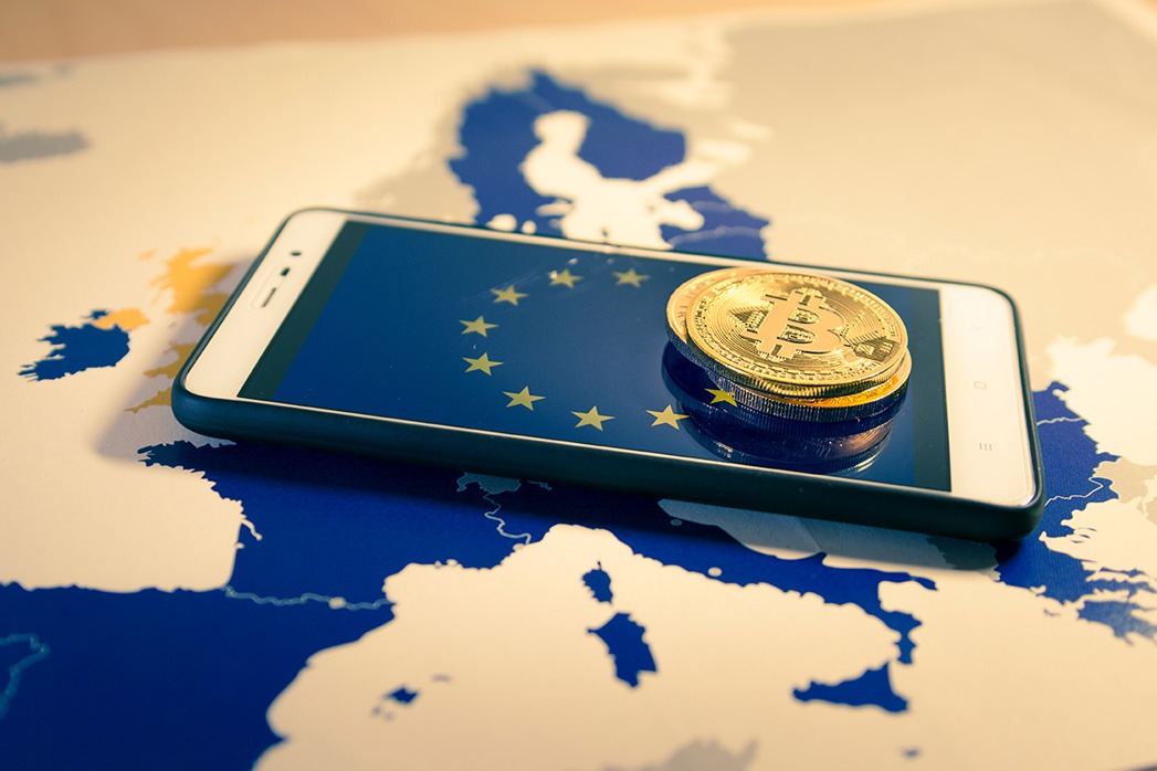 Financial concept with golden Bitcoin over smartphone, EU flag and map.