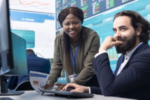 Team of diverse specialists review monthly cost and revenue elements on a computer.