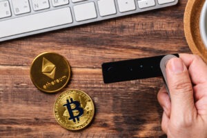 Hand holding a hardware wallet, transferring Bitcoin and Ethereum to it for safety.