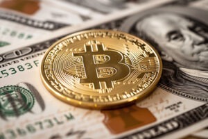 Golden symbolic coin Bitcoin on banknotes of one hundred dollars. Exchange bitcoin cash for a dollars. Cryptocurrency on US dollar bills.