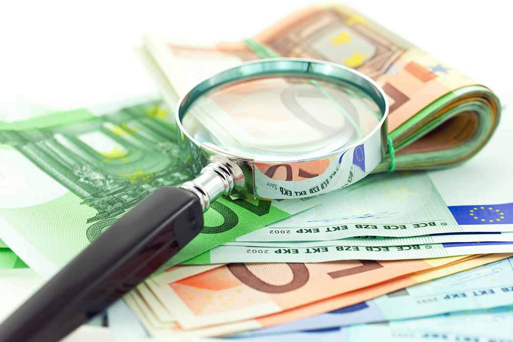 euro notes with magnifier on white background.