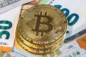 Close up of metal shiny bitcoin crypto currency coins on US dollar bills. Electronic decentralized.