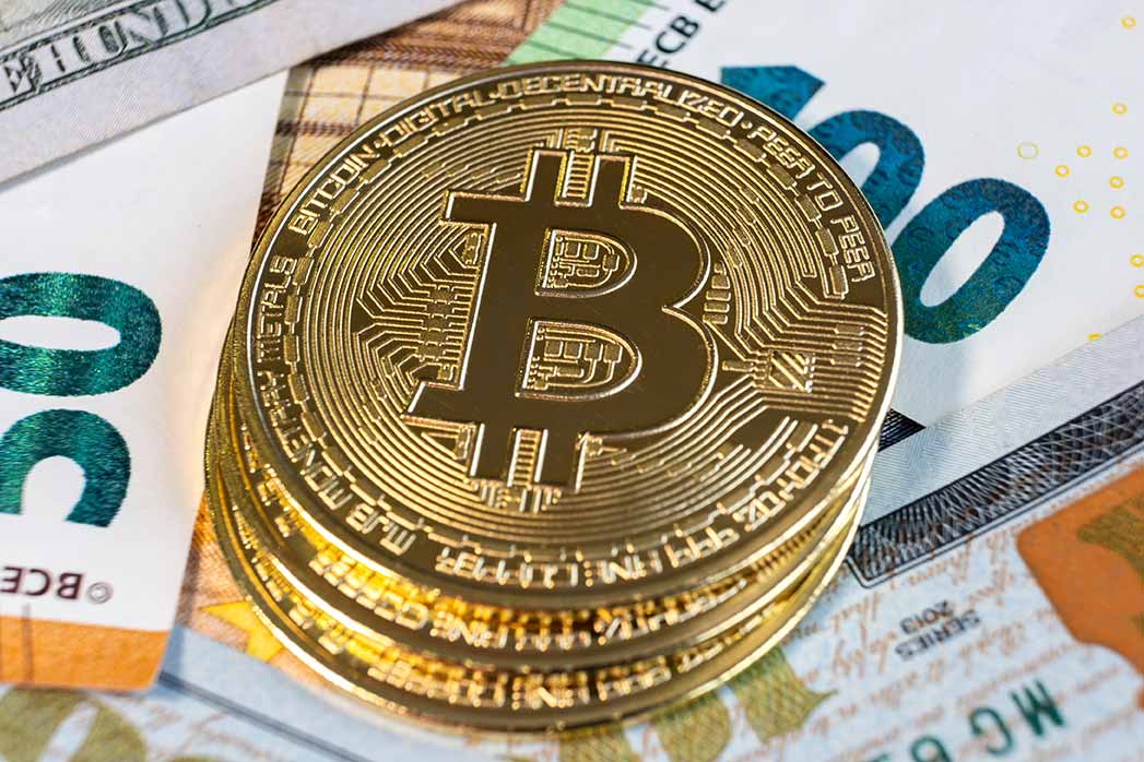 Close up of metal shiny bitcoin crypto currency coins on US dollar bills. Electronic decentralized.