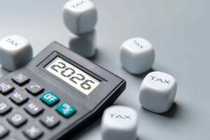 A calculator displaying the year 2026 surrounded by dice labelled TAX.