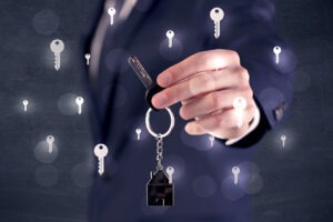 Businessman In Suit Holding Keys With Keys Graphics Around And Dark Background.