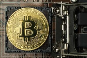 Golden bitcoin and computer chip in background.