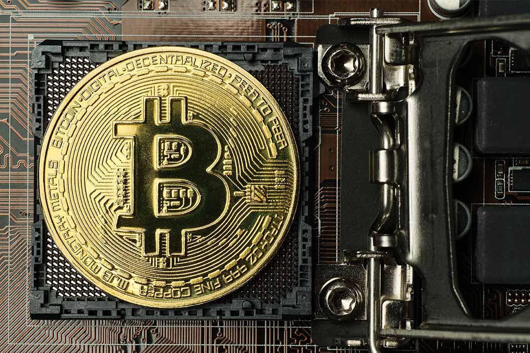 Golden bitcoin and computer chip in background.