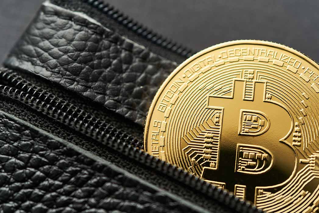 A bitcoin protruding from a leather wallet, Virtual cryptocurrency concept.