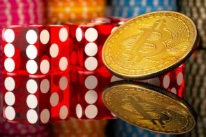 Bitcoin cryptocurrency gold coin, red dice and casino chips on a reflective surface. Set for games of chance, poker, casino entertainment. The concept of bets, risk, success and wealth.