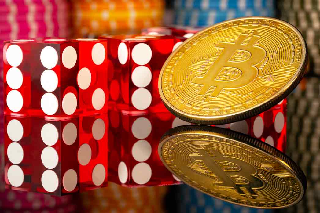 Bitcoin cryptocurrency gold coin, red dice and casino chips on a reflective surface. Set for games of chance, poker, casino entertainment. The concept of bets, risk, success and wealth.