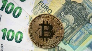 Bitcoin physical coin laying on top of 100 Euro bills.