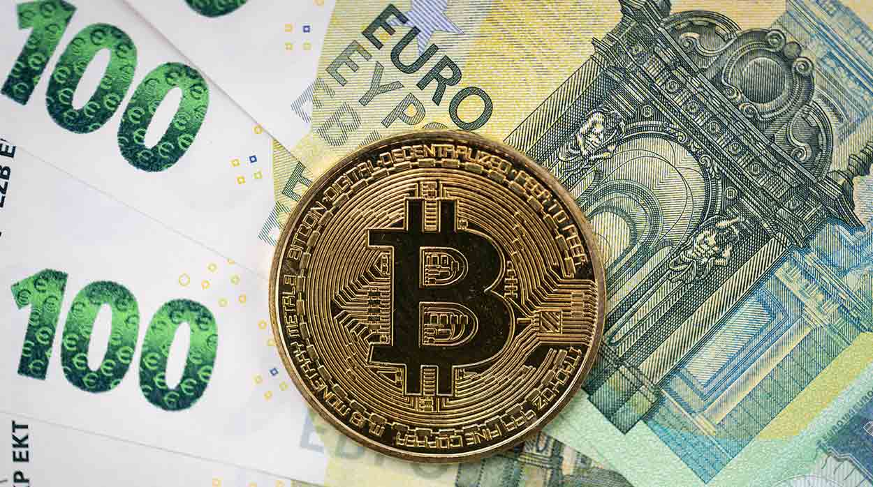 Bitcoin physical coin laying on top of 100 Euro bills.