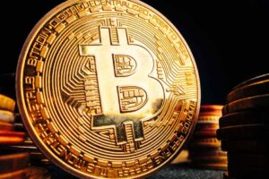Golden Bitcoin Coin on a Red Circuit Board.