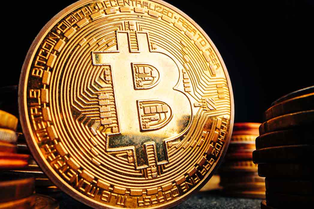 Golden Bitcoin Coin on a Red Circuit Board.