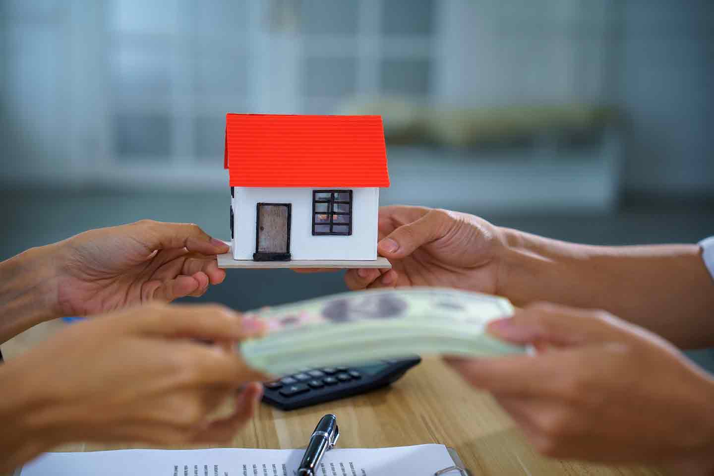 Real estate house model cash payment contract exchange office buyer seller show home purchase, mortgage loan approval, property sale closing on table with document, pen, calculator.