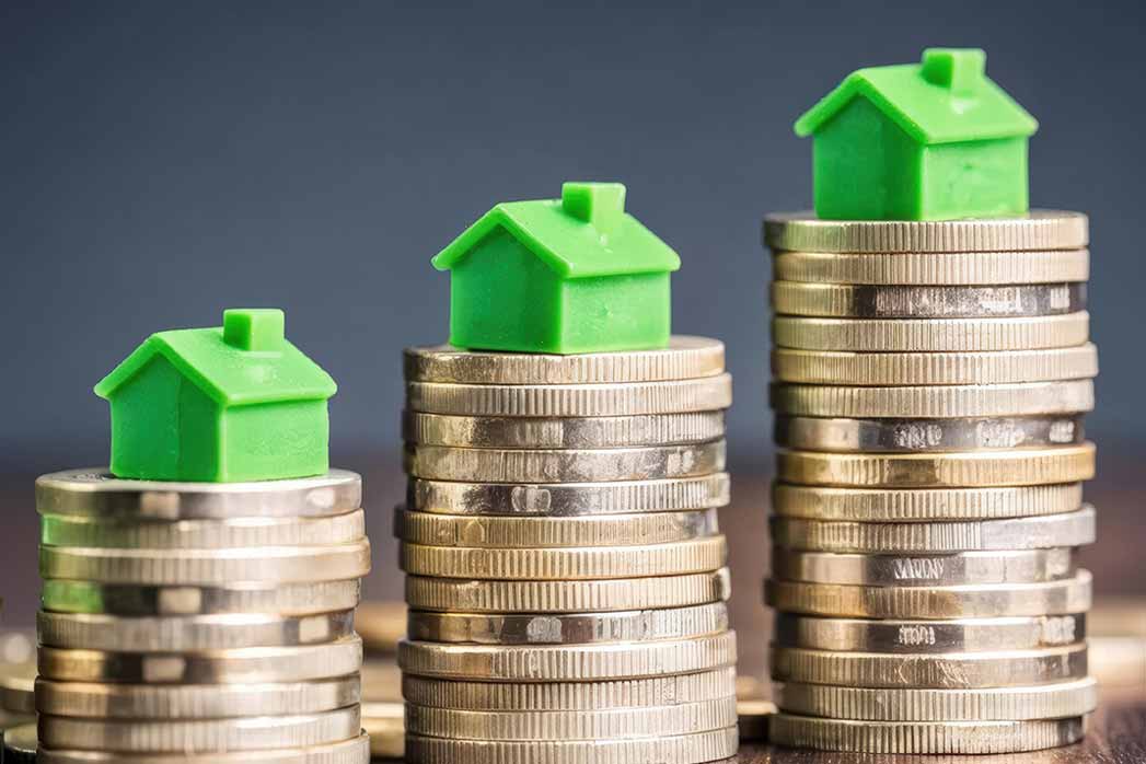 Green Toy Houses on Stacks of Shiny Coins.