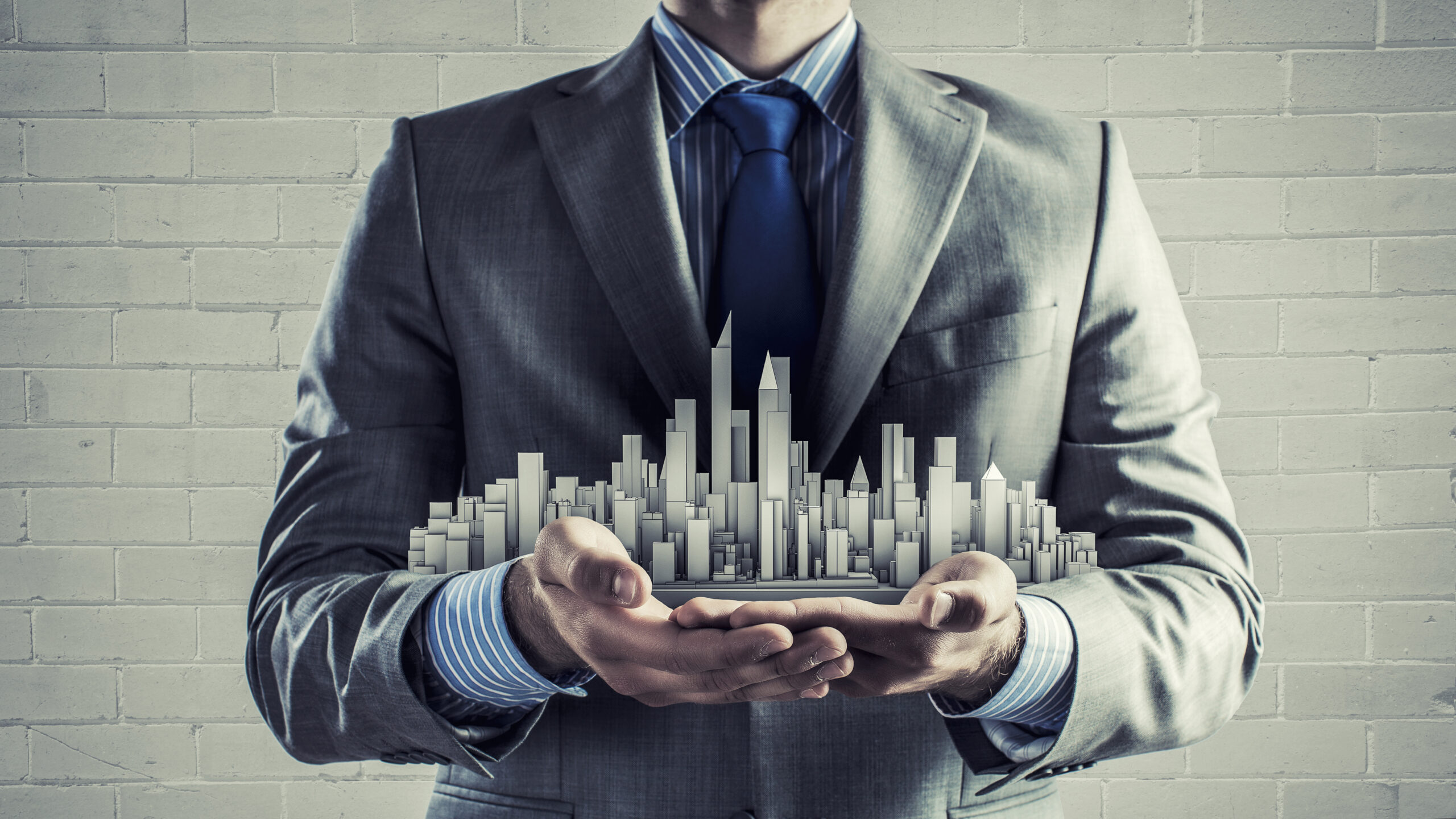 Close Up Of Businessman Hand Holding Construction Model.