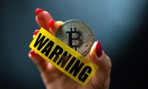 Bitcoin Warning Message in Hand with Red Nails.