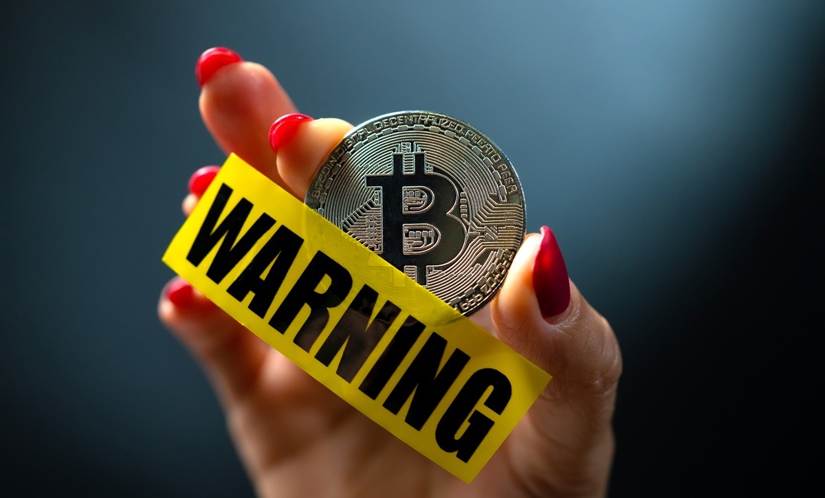 Bitcoin Warning Message in Hand with Red Nails.