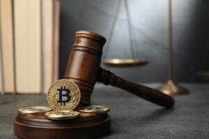 Cryptocurrency. Bitcoins, judge's gavel, books and scales on grey table, closeup
