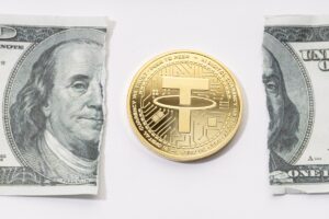 Tether USDT coin and ripped dollar bill. Broken USDT dollar parity concept